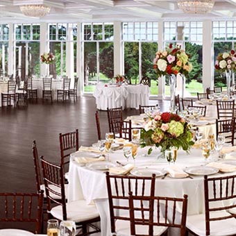 Reception tables decorated with white table cloths and multicolored flowers. 